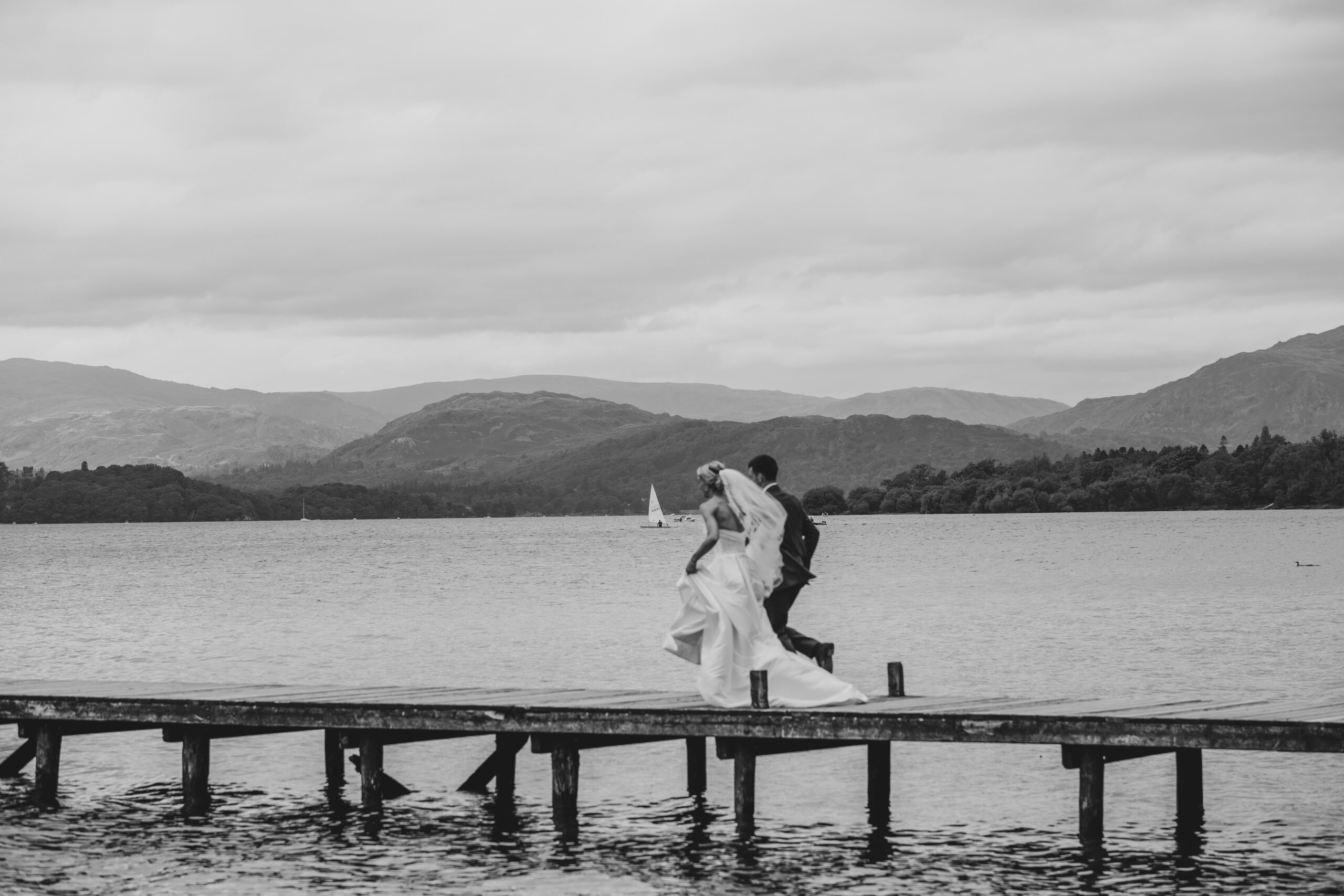 couple running down windermere jetty on wedding day